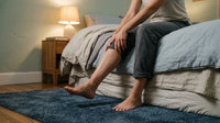 Personne assise au bord du lit tenant son mollet pendant une crampe nocturne à la jambe